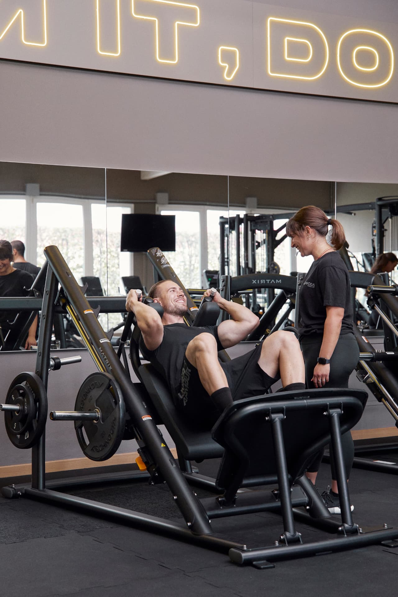 Atleta sul leg press con l'assistenza di un'istruttrice